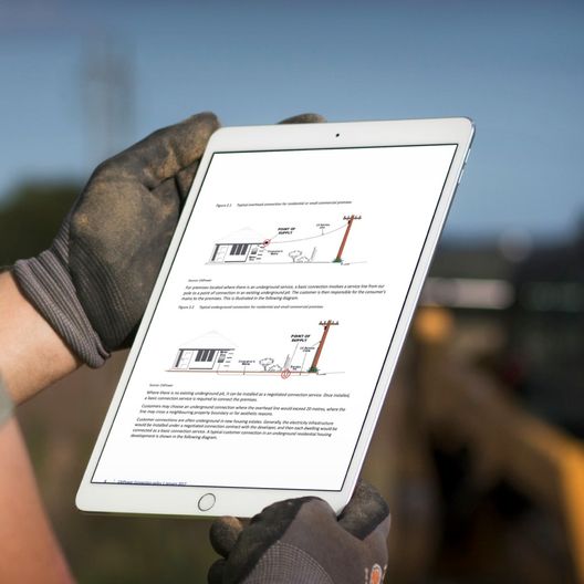 Person with gloves holding white tablet viewing graphics